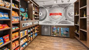 A snack and beverage kiosk with shelves stocked with various snacks and drinks, and a wall mural with a 'TREATS' sign.