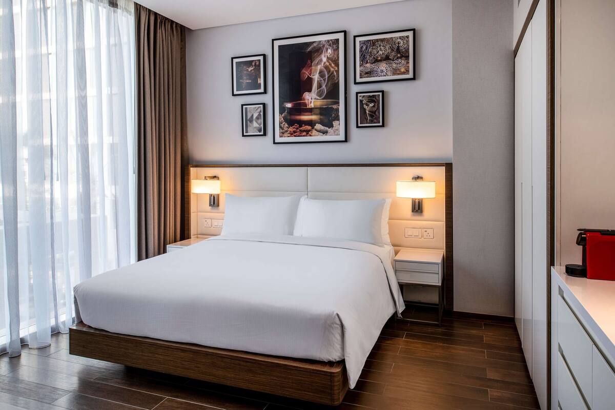 Ein modernes Hotelzimmer mit einem großen Bett, Nachttischlampen und einer Wand mit gerahmten Bildern.