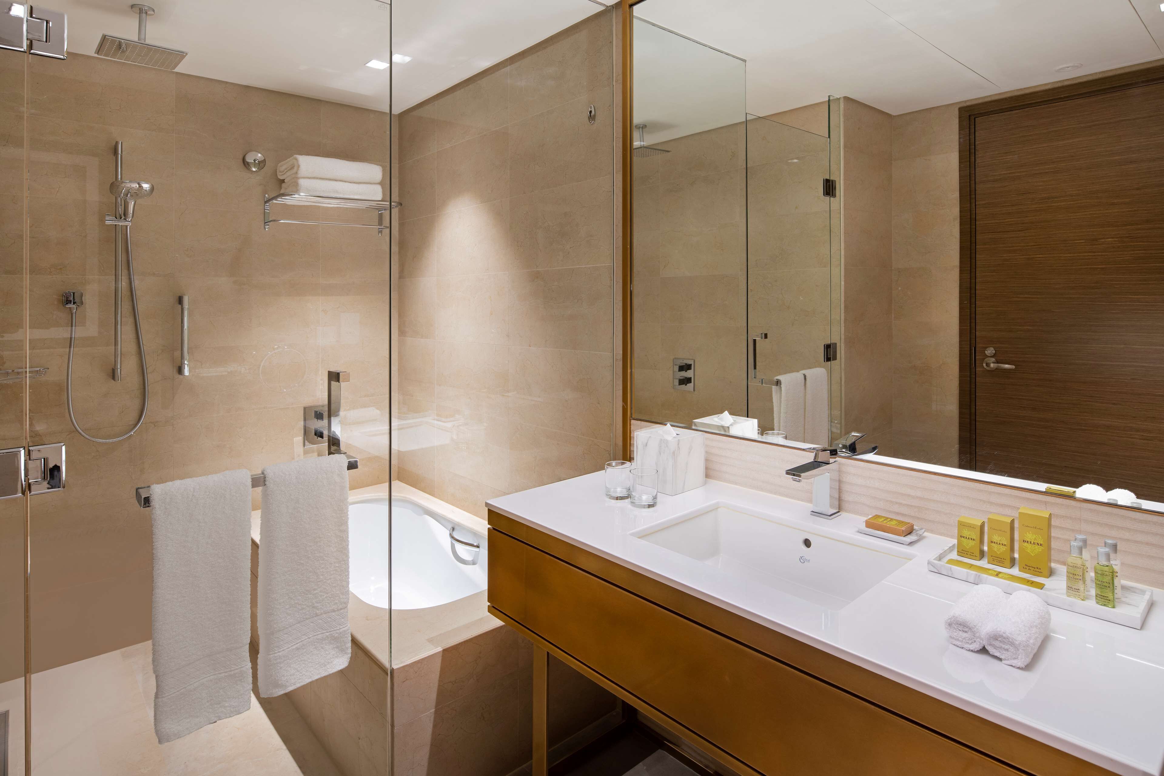 Een moderne badkamer met een douchecabine, een bad en een wastafel met een grote spiegel.