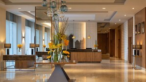 A modern hotel lobby with a central table, seating area, and a reception desk. - Hilton Garden Inn Riyadh Financial District (Riyadh)