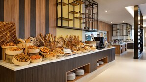 A buffet area with various breads, pastries, and utensils. - Hilton Garden Inn Riyadh Financial District (Riyadh)