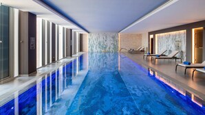 A long indoor swimming pool with blue lighting, lounge chairs, and a modern design. - Hilton Garden Inn Riyadh Financial District (Riyadh)