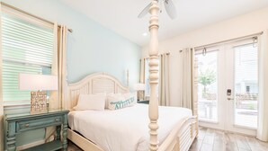 Une chambre à coucher avec un lit à baldaquin, une table de chevet, une commode et une fenêtre avec des stores.