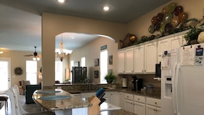 Una cocina moderna con muebles blancos, encimeras de granito y una isla central con asientos.