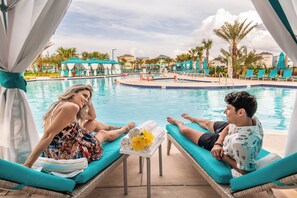 A poolside area with lounge chairs and a table with towels and a flower.