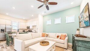A modern living room with a sectional sofa, a coffee table, and a dining area with a green chair.