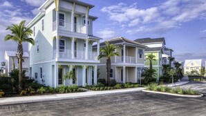 A multi-story residential building with balconies, surrounded by palm trees and a clear sky.