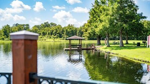 A gazebo on a lake with a wooden deck, surrounded by trees and a grassy area with picnic tables. - Hot tub!! Family Friendly - Loving Home (Kissimmee)