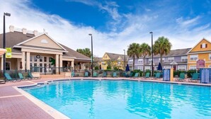 A swimming pool with lounge chairs and a building with a porch in the background. - Hot tub!! Family Friendly - Loving Home (Kissimmee)