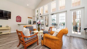 A spacious living area with wicker furniture, a small round table, and a flat-screen TV mounted on the wall. - Hot tub!! Family Friendly - Loving Home (Kissimmee)
