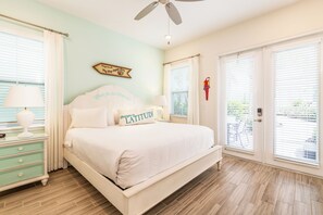 A bedroom with a bed, nightstands, a ceiling fan, and a window with blinds.