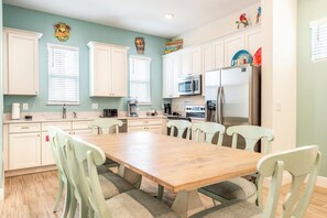 A kitchen with white cabinets, a wooden table, and light green chairs.