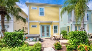 A two-story yellow building with a patio area featuring outdoor seating and a hot tub.