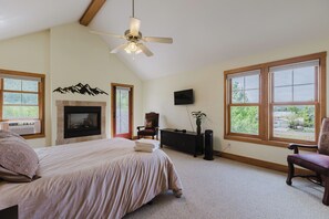 A bedroom with a bed, a fireplace, a television, and large windows. - Overlook San Juan River, Walk to Town, Quality 2 BD/2BA (Pagosa Springs)