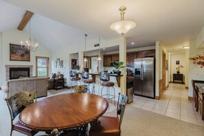 A spacious living room with a fireplace, a dining area with a wooden table and chairs, and a kitchen with modern appliances. - Overlook San Juan River, Walk to Town, Quality 2 BD/2BA (Pagosa Springs)