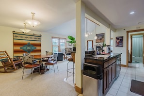 A spacious kitchen with a dining area, a large rug, and a hanging light fixture.