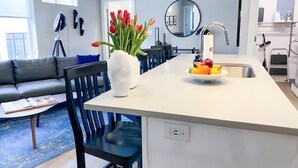 A modern kitchen with a white countertop, a sink, and a vase of red tulips.