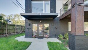 A modern two-story house with a flat roof, a visible number '119' on the facade, and a front entrance with glass doors.