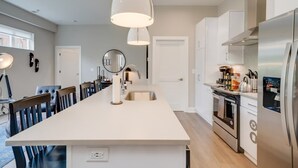 A modern kitchen with a central island, stainless steel appliances, and pendant lighting.