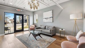 Ein modernes Interieur mit einer Couch, einem Glastisch, einem Teppich, einer Lampe und einem Gemälde an der Wand.