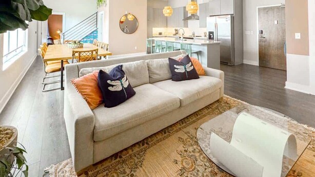 Ein modernes Wohnzimmer mit Sofa, Couchtisch und Essbereich mit Stühlen.