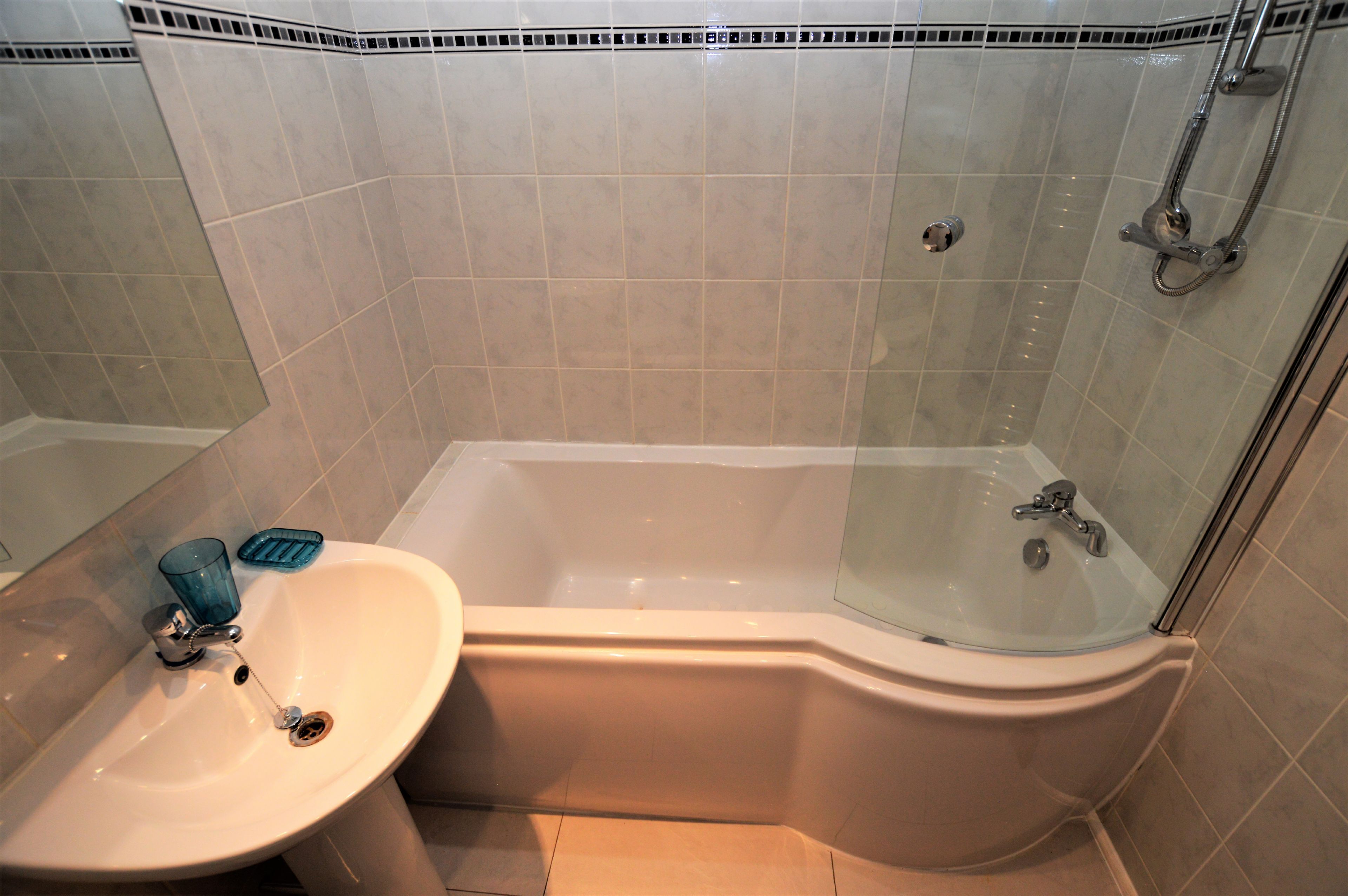 A bathroom with a bathtub, a sink, and a glass shower enclosure.