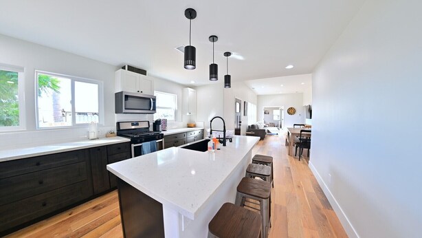 A modern kitchen with a central island, dark wood cabinets, and a large window. - Family Retreat in The Village - Yard & Patio (Arroyo Grande)
