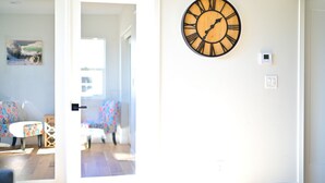A room with a wooden wall clock, a door leading to another room, and a small table with chairs. - Family Retreat in The Village - Yard & Patio (Arroyo Grande)