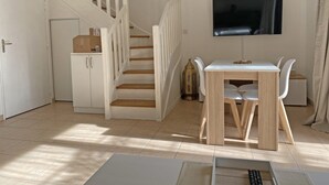 Un salon moderne avec un escalier, un coin repas et un téléviseur fixé au mur.