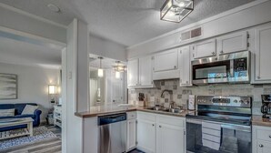 A modern kitchen with white cabinetry, stainless steel appliances, and a dishwasher. - 443 By the Sea - Gated Myrtle Beach Resort - Near MYR (Myrtle Beach)