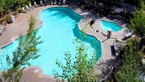 A swimming pool surrounded by lounge chairs and a small hot tub, with trees and a building in the background. - Spacious Corner VILLAGE Condo 2BD/2BA #2202 w/ Ski-back Trail close to GONDOLA (Mammoth Lakes)