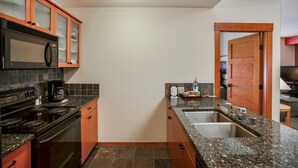 A compact kitchen with a stove, microwave, and granite countertops. - Spacious Corner VILLAGE Condo 2BD/2BA #2202 w/ Ski-back Trail close to GONDOLA (Mammoth Lakes)