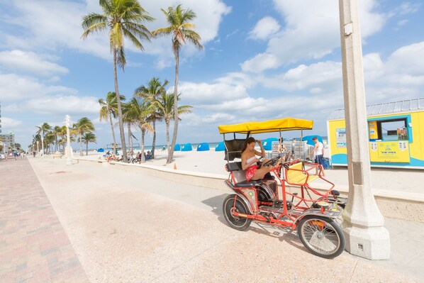 A beachside scene with a red bicycle cart, palm trees, and a yellow kiosk.
