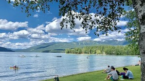 A lakeside view with boats, grassy areas, and people relaxing.