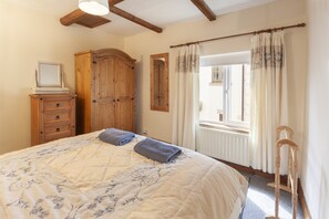 A bedroom with a bed, wooden wardrobe, and a window with curtains.