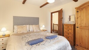 Ein Schlafzimmer mit Bett, Nachttischen, Kommode, Spiegel und Kleiderschrank.