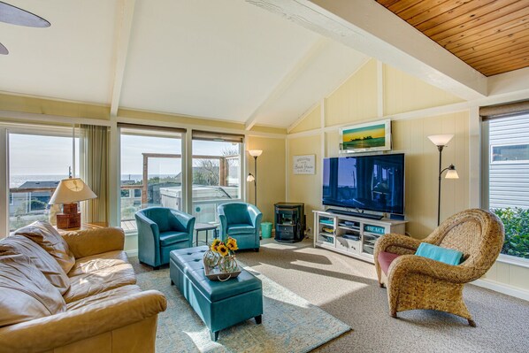 A spacious living room with a large TV, comfortable seating, and a view of the ocean. - Hot Tub! Ocean Views and Short Walk to Sandy Beach! Game Room! (Waldport)