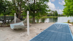 A hammock and shuffleboard table by a lake.