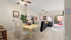 A dining area with a table and chairs, a ceiling fan, and a Christmas tree.