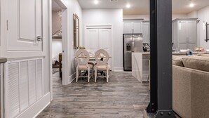 Une cuisine moderne avec des meubles blancs, un réfrigérateur en acier inoxydable et un coin repas comprenant une table et des chaises.