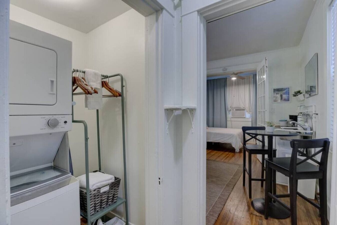 Een kleine hotelkamer met kitchenette, een bed, een tafeltje en een stoel.