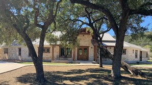 A stone building with a prominent entrance and large windows. - Double L River House @ Frio Premier Rental Homes (Concan)