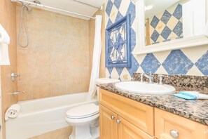 Un baño con bañera, inodoro, lavamanos y tocador.