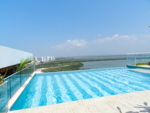 A rooftop infinity pool with a clear view of a body of water and distant buildings. - Martinique Delux with Private Hot Tub (Cartagena)