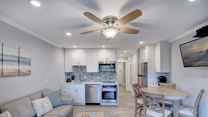 A modern kitchen with white cabinets, a built-in oven, and a microwave. There is a dining area with a round table and chairs. - Awesome Ocean View! Coligny Area! Updated and CLEAN 1 Bedroom! #380 (Hilton Head Island)