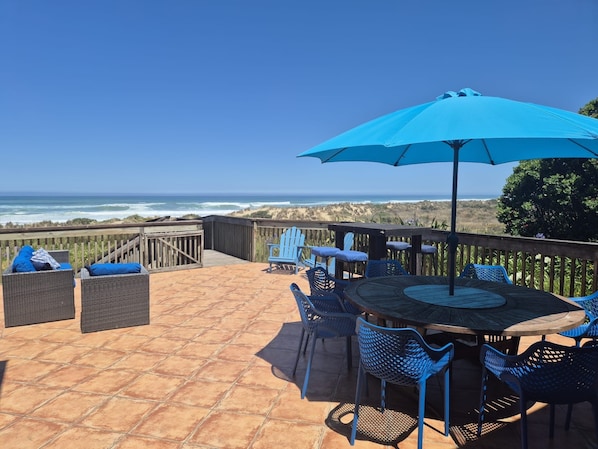 A patio with outdoor furniture, a table, and a view of the ocean.