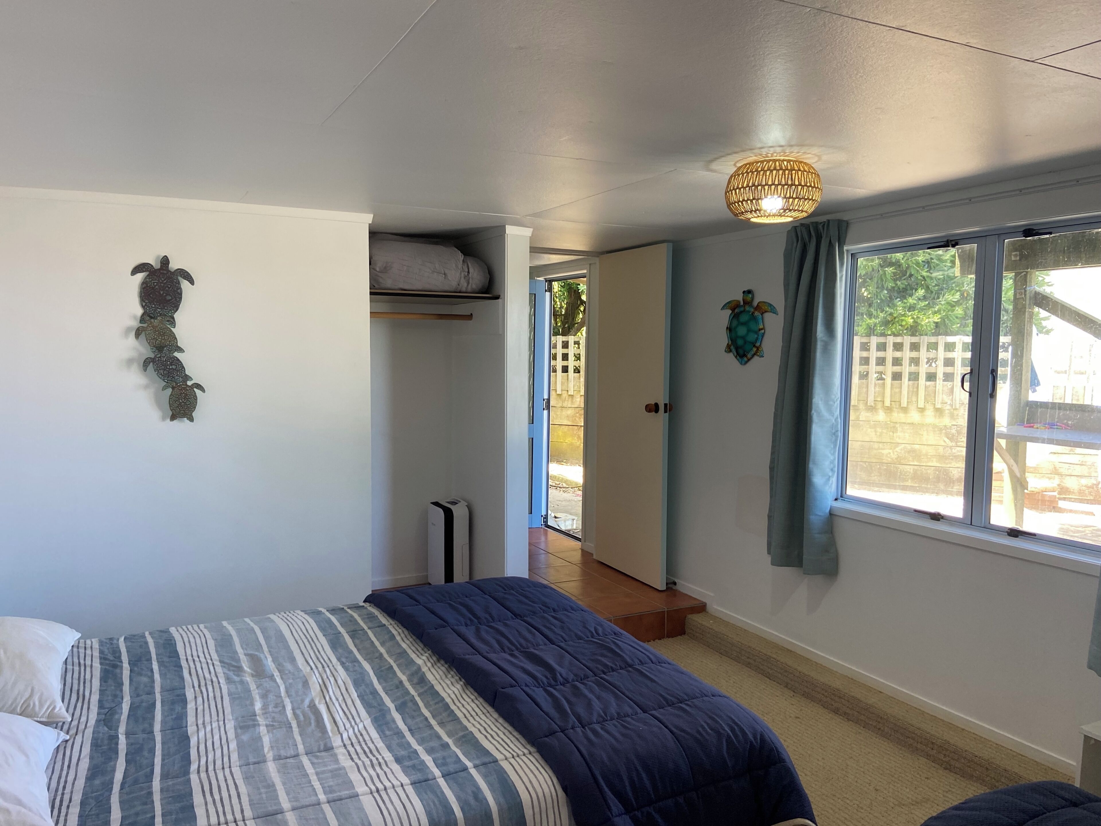 Een slaapkamer met een bed, een kledingkast, een plafondlamp en een raam met uitzicht.