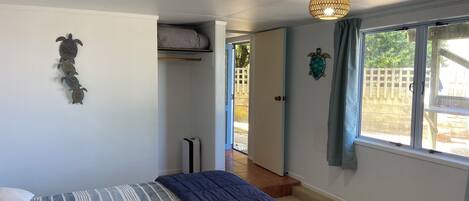 Een slaapkamer met een bed, een kledingkast, een plafondlamp en een raam met uitzicht.