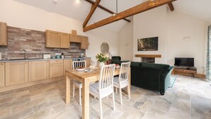 A modern kitchen with wooden cabinets, a stone backsplash, and a dining area with a wooden table and white chairs. - A marketing that sleeps 2 guests  in 1 bedroom (Trowbridge)