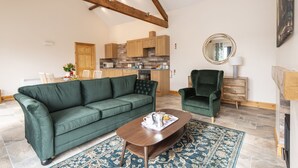 A modern living room with a green sofa, a wooden coffee table, and a patterned rug. - A marketing that sleeps 2 guests  in 1 bedroom (Trowbridge)